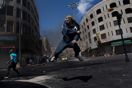 A Palestinian throws a stone towards Israeli forces