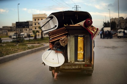 Aleppo, Syria: a boy holds a satellite dish as he travels on the back of a truck